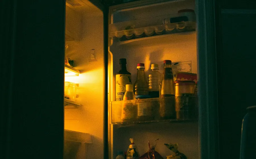 Refrigerador abierto con la luz interior encendida en una cocina oscura